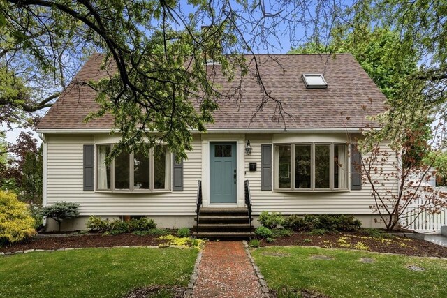 new england style home featuring entry steps, roof with shingles, and a front lawn