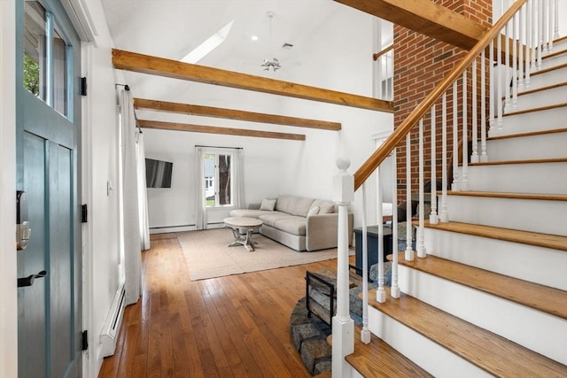 staircase with baseboard heating, hardwood / wood-style flooring, beamed ceiling, and high vaulted ceiling