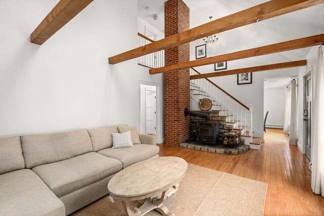 living area with wood-type flooring, a wood stove, stairway, beam ceiling, and high vaulted ceiling