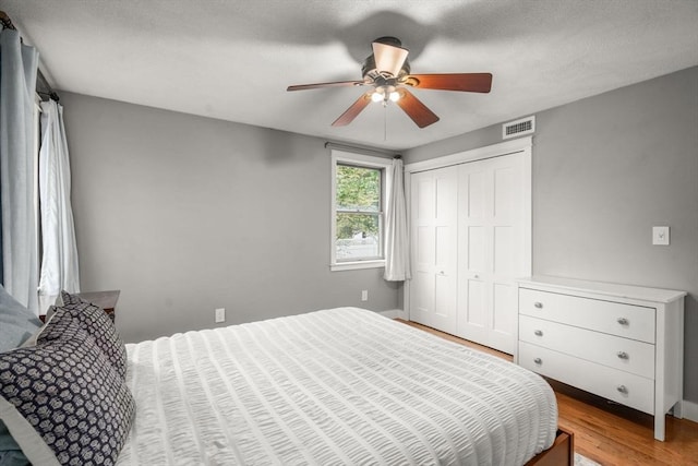 bedroom featuring light wood finished floors, a closet, baseboards, and a ceiling fan