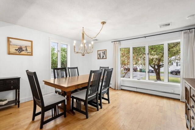 dining room with a baseboard radiator, a chandelier, and light wood-style floors