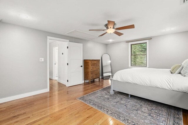 bedroom with attic access, light wood finished floors, ceiling fan, and baseboards