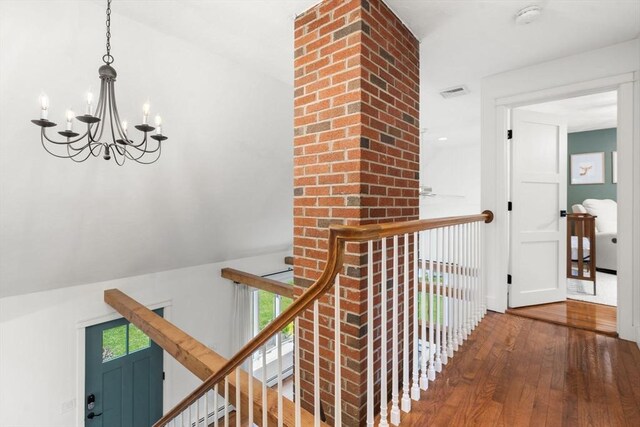 corridor with hardwood / wood-style floors, a chandelier, and an upstairs landing