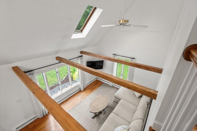 living area with a baseboard heating unit, a ceiling fan, a skylight, lofted ceiling, and wood finished floors
