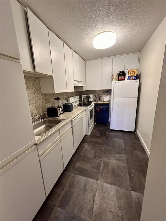 kitchen with under cabinet range hood, white cabinets, white appliances, and a sink