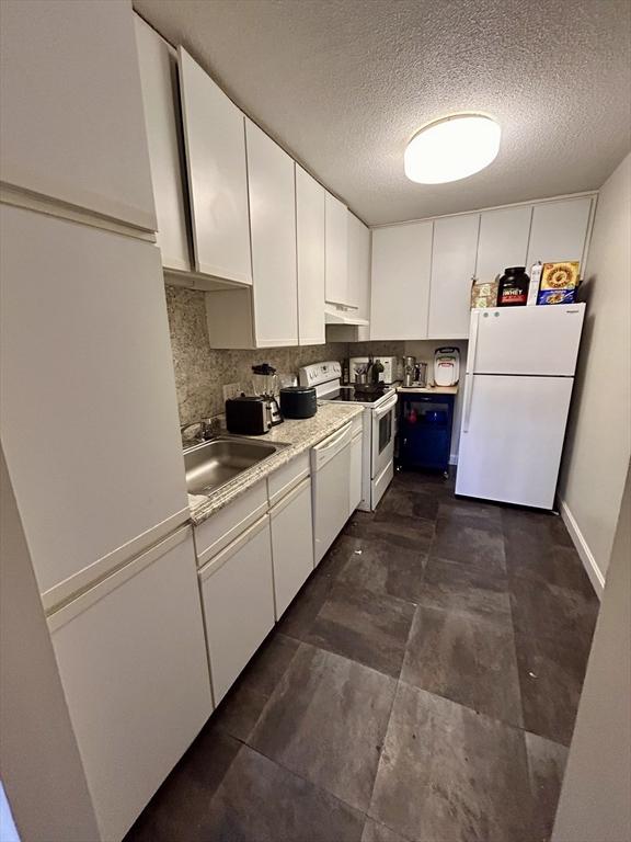 kitchen featuring tasteful backsplash, white cabinets, white appliances, and a sink