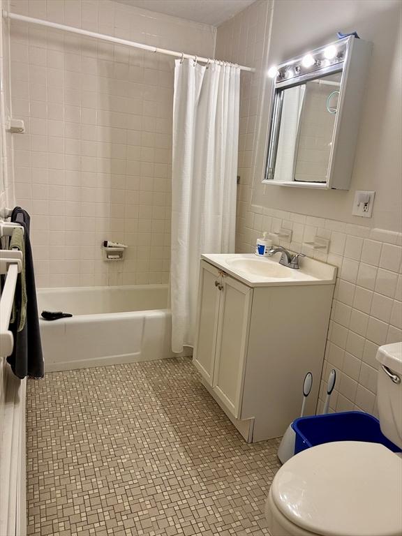 bathroom featuring tile walls, toilet, shower / bath combo, and tile patterned floors