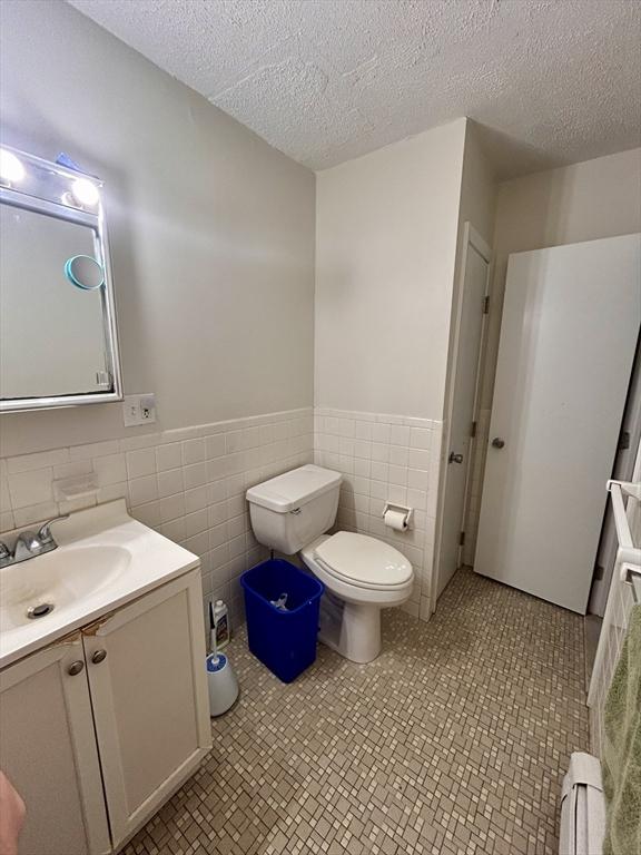 bathroom with toilet, wainscoting, vanity, and a textured ceiling