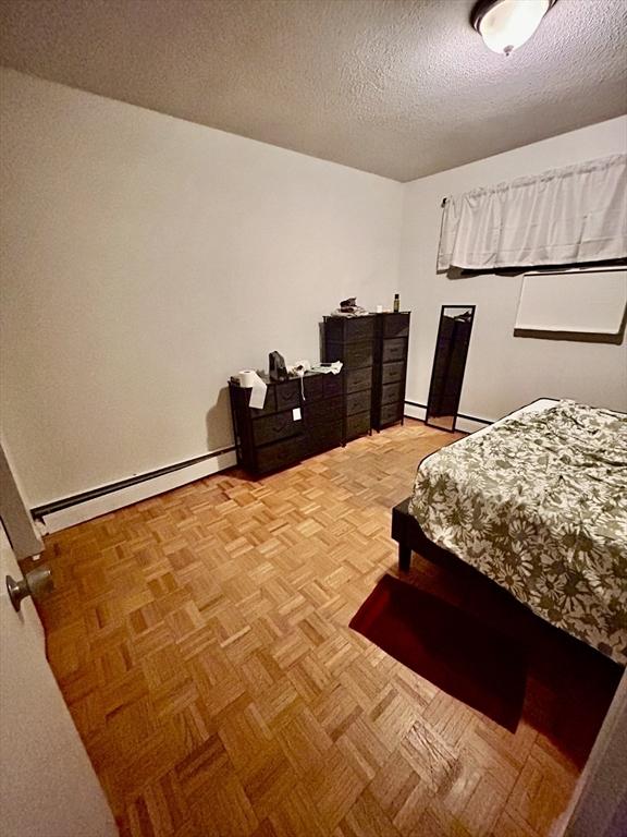 bedroom with a baseboard heating unit and a textured ceiling