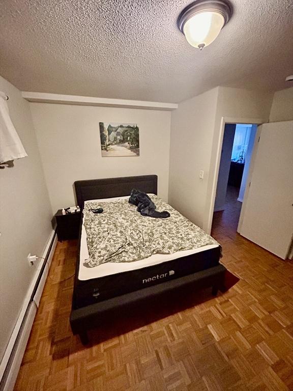 bedroom with a textured ceiling and a baseboard radiator