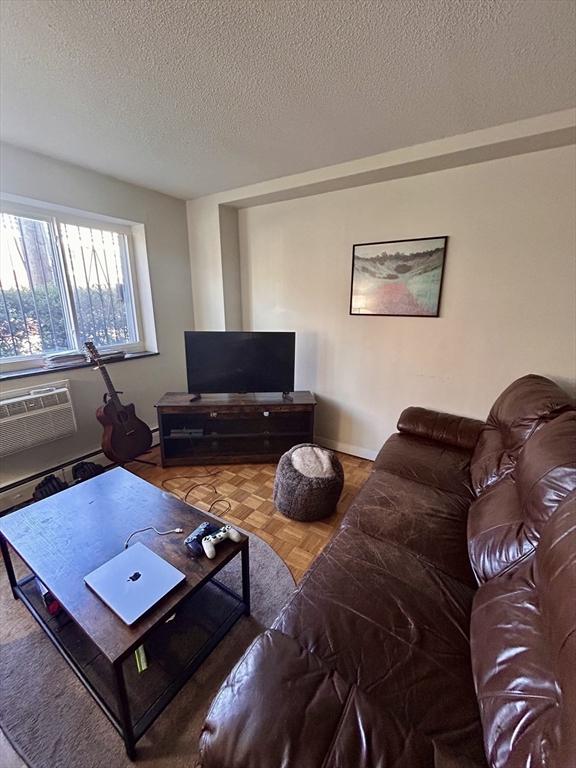 living area with a textured ceiling and a wall mounted AC