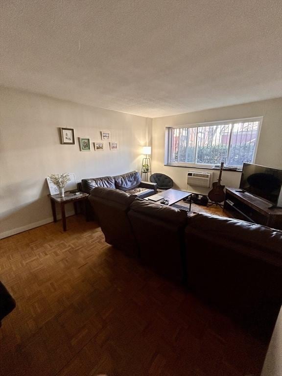 living room featuring baseboards, a wall mounted air conditioner, and a textured ceiling