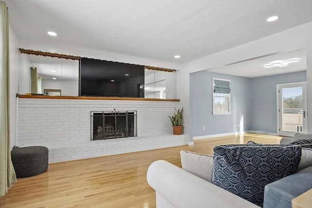 living room featuring recessed lighting, a brick fireplace, baseboards, and wood finished floors