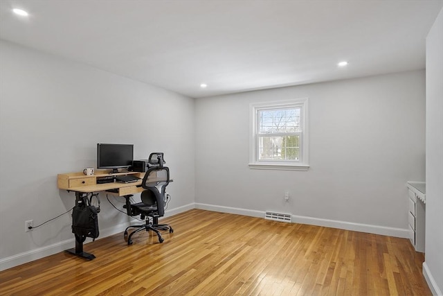 office area with light wood-style floors, visible vents, and baseboards