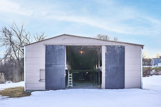 snow covered structure featuring an outbuilding