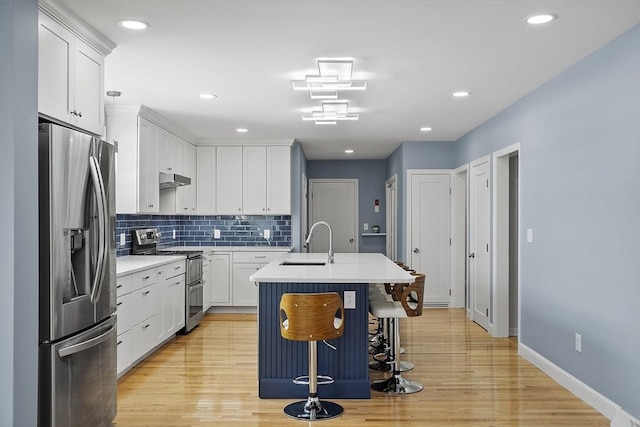 kitchen with appliances with stainless steel finishes, light countertops, a sink, and tasteful backsplash