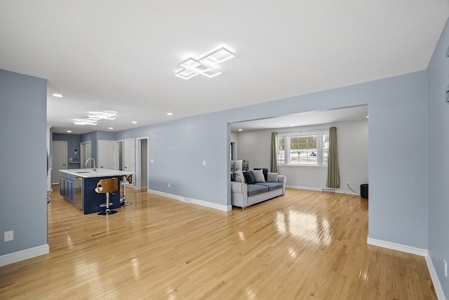 living room featuring light wood finished floors, baseboards, and recessed lighting