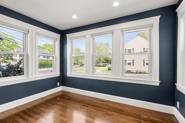 empty room with a healthy amount of sunlight, baseboards, recessed lighting, and dark wood-type flooring