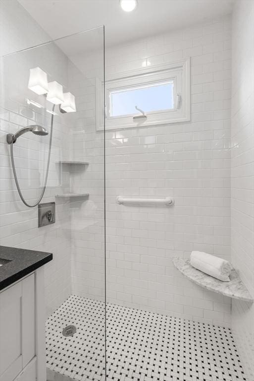 bathroom with a tile shower and vanity