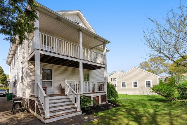 rear view of house featuring covered porch, a lawn, and a balcony