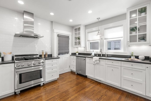 kitchen featuring dark countertops, backsplash, stainless steel appliances, and wall chimney exhaust hood