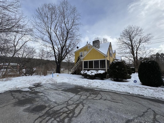 view of snowy exterior with a chimney and stairway