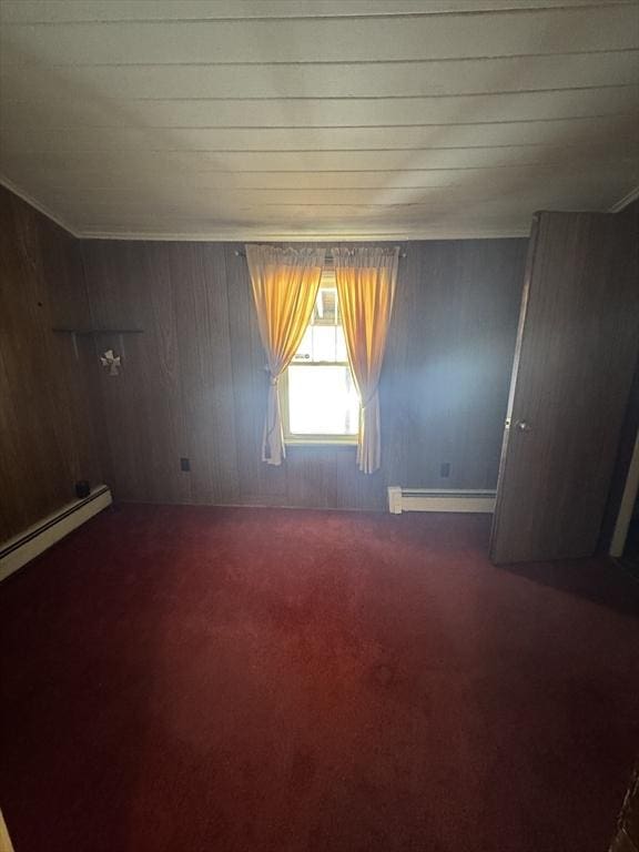 empty room featuring carpet, crown molding, and baseboard heating