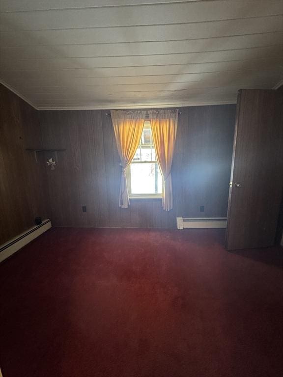 empty room featuring ornamental molding, baseboard heating, and carpet flooring