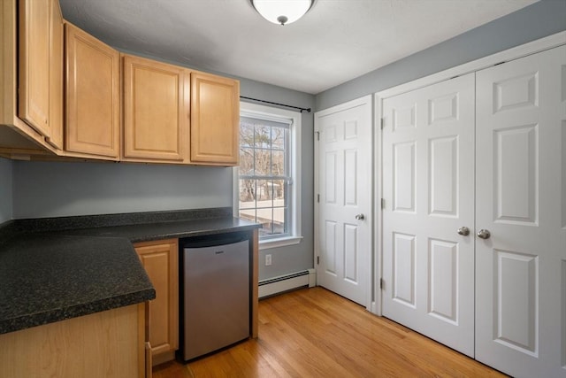 kitchen featuring a baseboard radiator, light brown cabinets, light wood-style flooring, dishwasher, and dark countertops