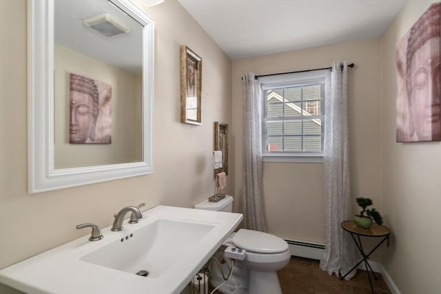 bathroom featuring a baseboard radiator, toilet, a sink, tile patterned flooring, and baseboards