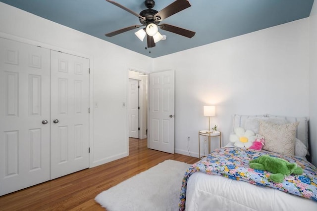 bedroom with a closet, wood finished floors, a ceiling fan, and baseboards