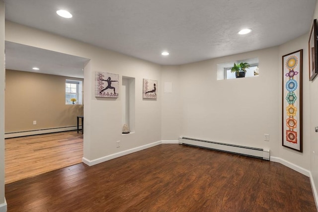 below grade area featuring dark wood-type flooring, a baseboard radiator, baseboards, and recessed lighting