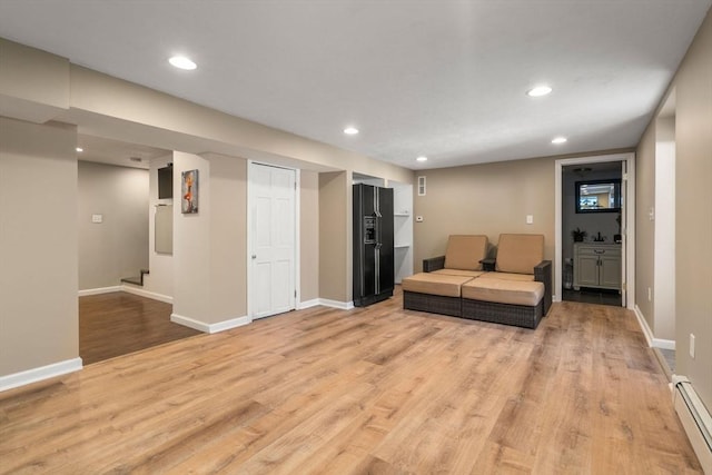 living room featuring baseboards, baseboard heating, light wood-style flooring, and recessed lighting