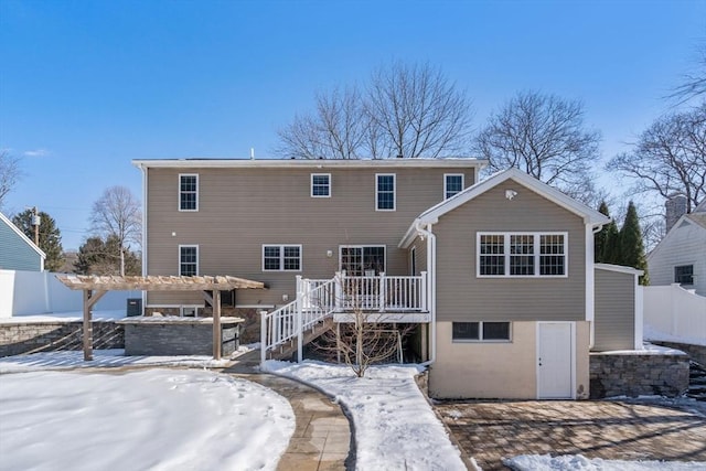 snow covered property with fence, a wooden deck, and a pergola