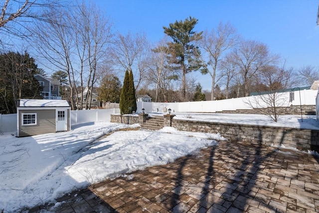 yard covered in snow featuring a shed, an outdoor structure, and a fenced backyard