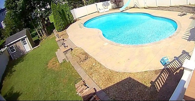 view of pool featuring an outbuilding, a water slide, a fenced backyard, and a fenced in pool