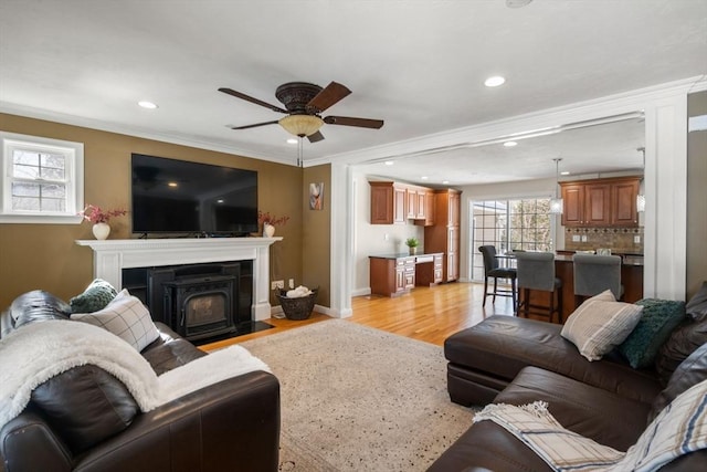 living area featuring recessed lighting, a ceiling fan, baseboards, light wood finished floors, and crown molding