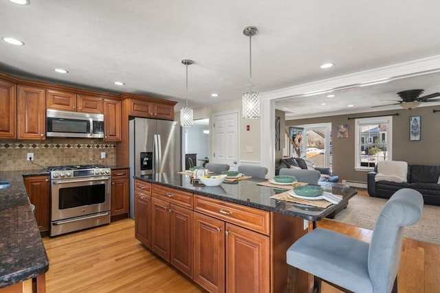 kitchen featuring appliances with stainless steel finishes, open floor plan, pendant lighting, and brown cabinets