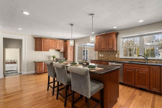 kitchen with a sink, decorative light fixtures, stainless steel dishwasher, and a center island