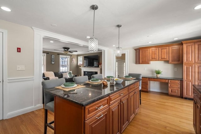 kitchen with a breakfast bar area, open floor plan, a center island, built in desk, and pendant lighting