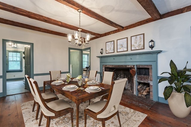 dining area with dark wood-type flooring, beamed ceiling, a chandelier, and a fireplace