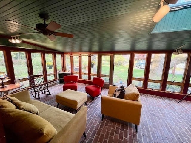 sunroom with lofted ceiling with skylight, wood ceiling, and ceiling fan