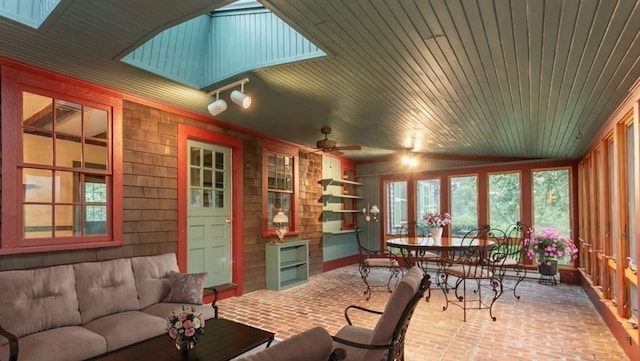 sunroom featuring vaulted ceiling with skylight, wood ceiling, and ceiling fan