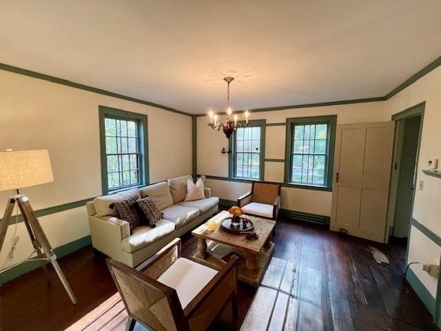 living room featuring crown molding, a healthy amount of sunlight, a notable chandelier, and dark hardwood / wood-style flooring