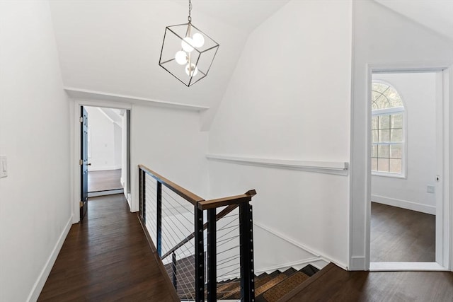 corridor featuring dark wood-type flooring, baseboard heating, an inviting chandelier, and vaulted ceiling