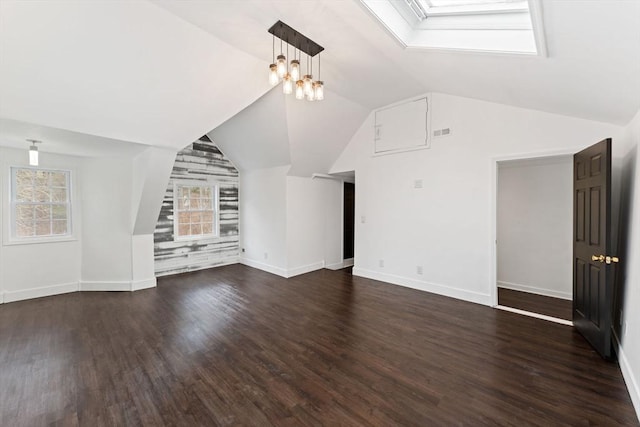 unfurnished living room with dark wood-type flooring, lofted ceiling with skylight, and an inviting chandelier