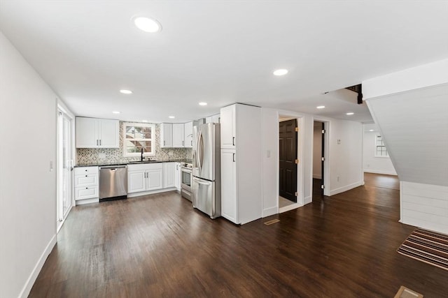 kitchen with stainless steel appliances, tasteful backsplash, dark wood-type flooring, white cabinets, and sink