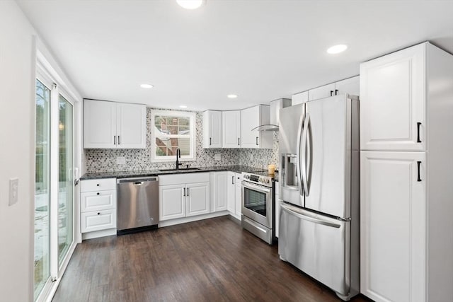 kitchen featuring white cabinets, wall chimney exhaust hood, stainless steel appliances, sink, and dark hardwood / wood-style floors