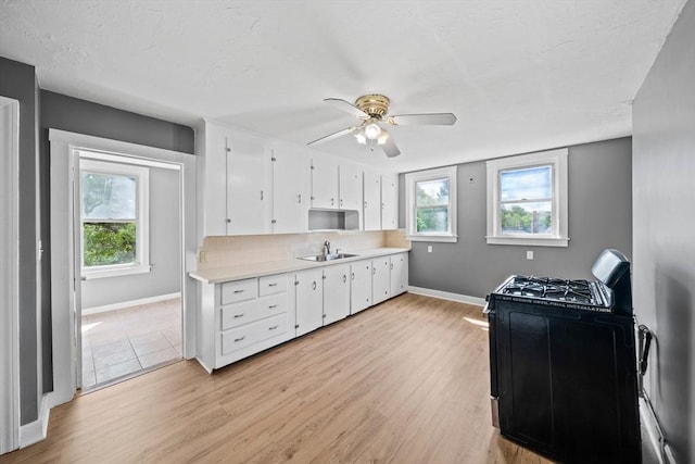 84 Tremont St, Taunton, MA 02780 - kitchen featuring light countertops, gas stove, baseboards, white cabinetry, and plenty of natural light