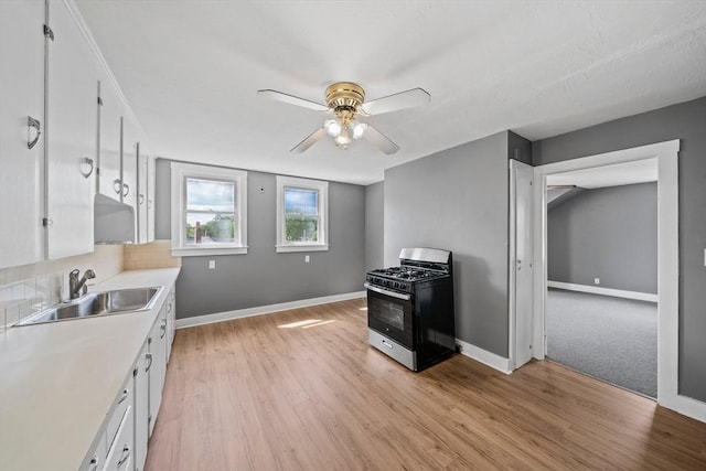 84 Tremont St, Taunton, MA 02780 - kitchen with black range with gas stovetop, a sink, white cabinetry, ceiling fan, and baseboards